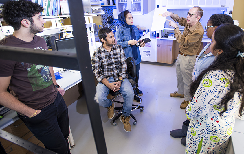 Professor Douglas Root (fourth from left) explains the principals of the gravitational force spectrometer for single molecule force spectroscopy, a research technique developed in his lab.